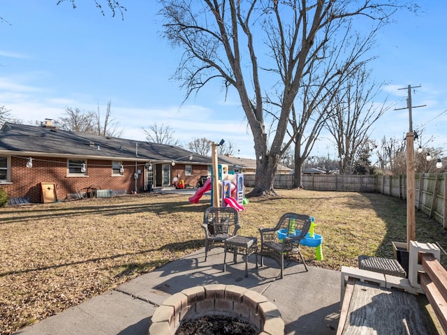 view of yard with a patio area, an outdoor fire pit, a playground, and a fenced backyard