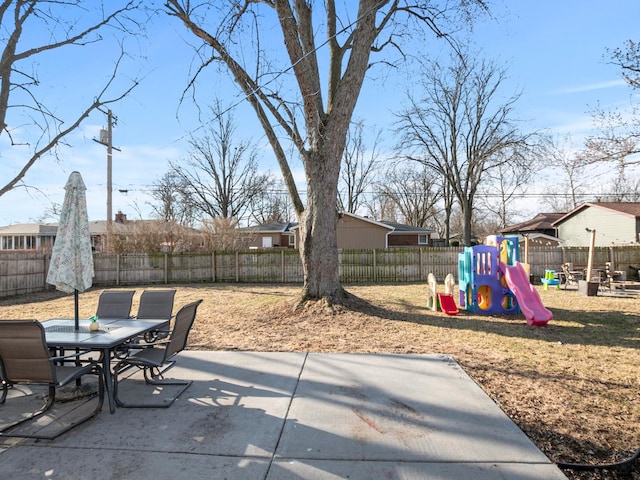 view of patio / terrace with outdoor dining area, a playground, and a fenced backyard