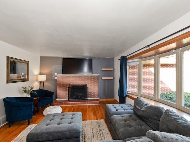 living room with a fireplace, baseboards, and wood finished floors