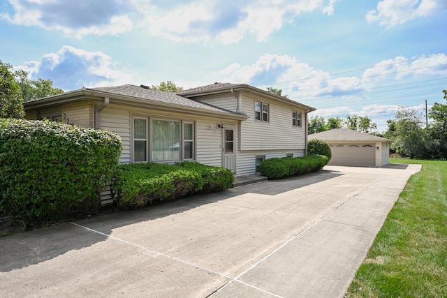 split level home featuring roof with shingles, an outdoor structure, and a detached garage