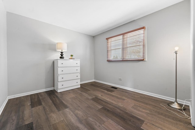 unfurnished bedroom with dark wood-style floors, visible vents, and baseboards