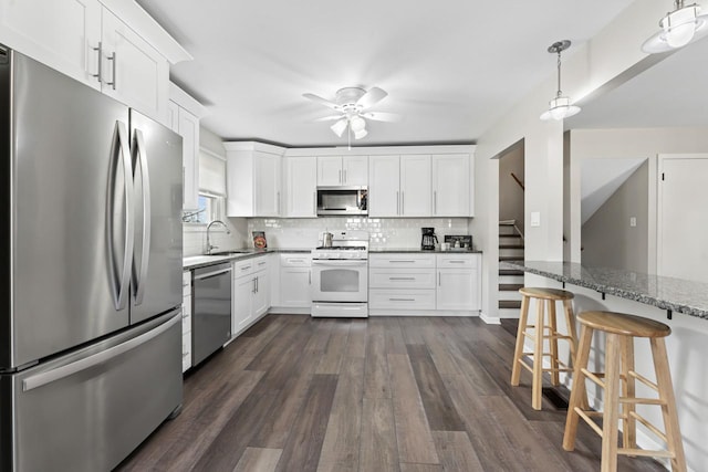 kitchen featuring appliances with stainless steel finishes, dark wood-style flooring, white cabinets, and decorative backsplash