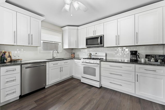 kitchen featuring dark wood finished floors, stainless steel appliances, decorative backsplash, white cabinets, and a sink