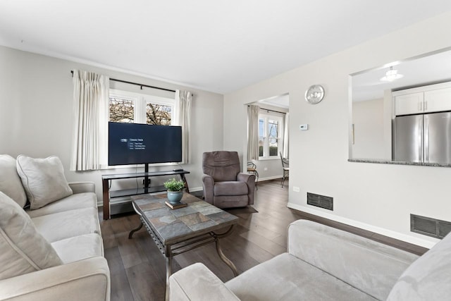 living area with wood-type flooring, visible vents, and baseboards