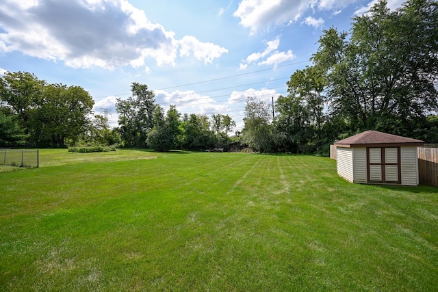 view of yard featuring a shed, fence, and an outbuilding