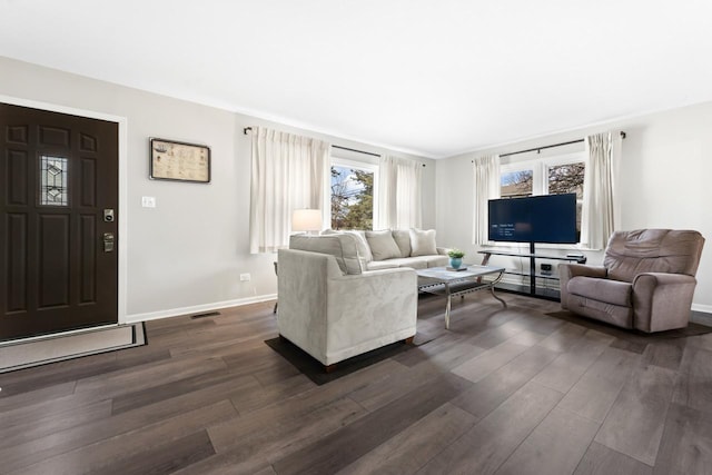 living room featuring dark wood-style flooring, visible vents, and baseboards