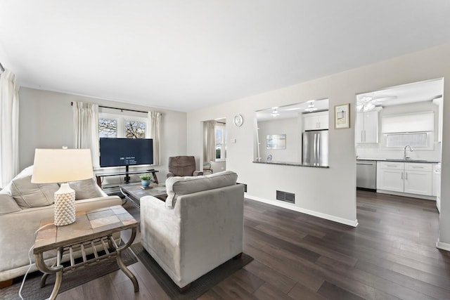 living area with dark wood-style floors, baseboards, and visible vents