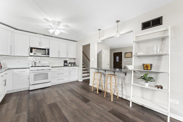 kitchen with gas range gas stove, dark wood-type flooring, visible vents, open shelves, and stainless steel microwave