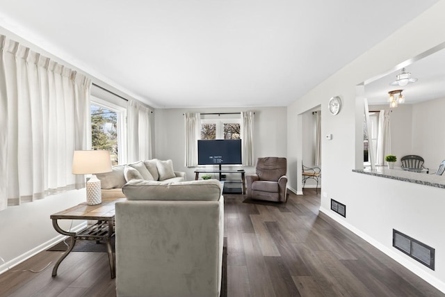 living area featuring dark wood-style floors, a wealth of natural light, and visible vents