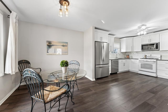 kitchen with dark wood finished floors, stainless steel appliances, backsplash, white cabinets, and a sink