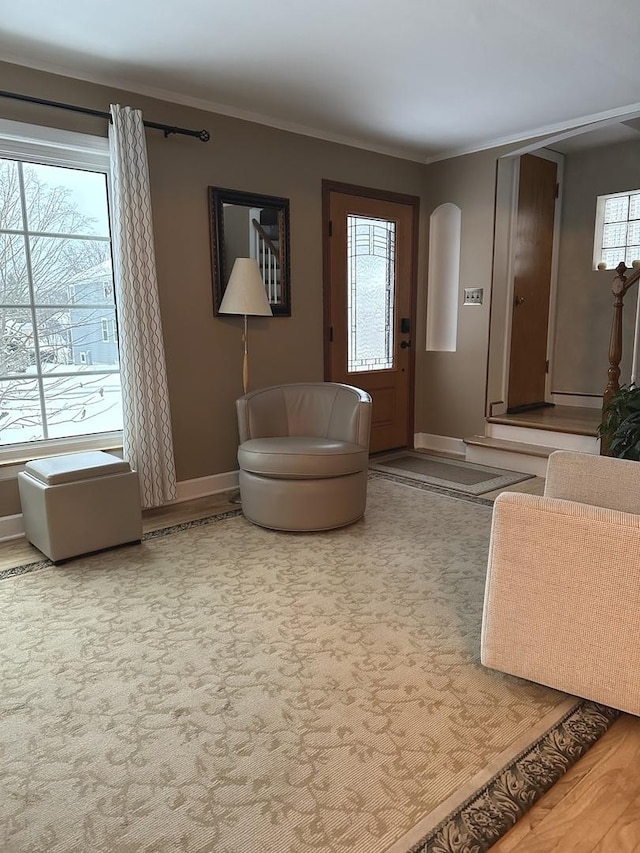 living area with crown molding, arched walkways, plenty of natural light, and baseboards