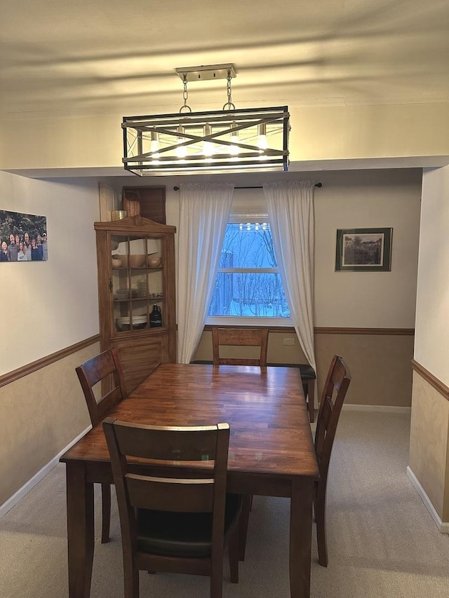 carpeted dining space with an inviting chandelier and baseboards