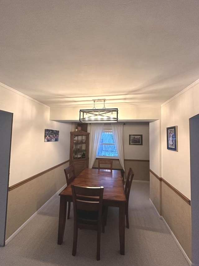 carpeted dining room featuring ornamental molding and baseboards