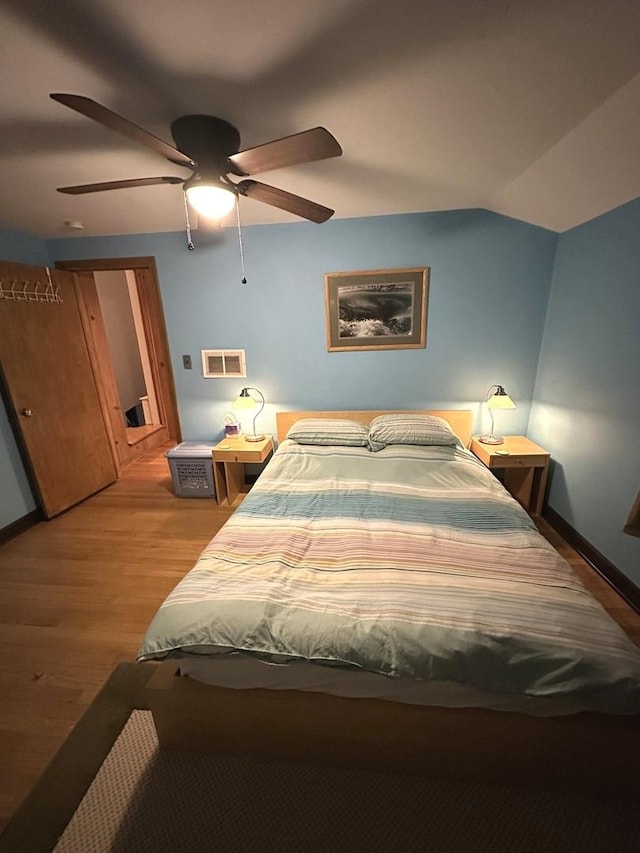 bedroom featuring visible vents, baseboards, a ceiling fan, light wood-style flooring, and vaulted ceiling