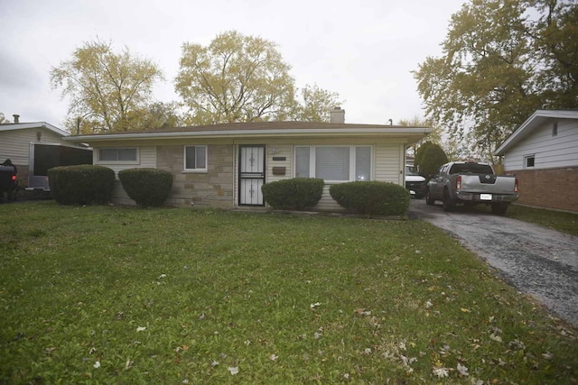 view of front of house with stone siding, aphalt driveway, a chimney, and a front yard