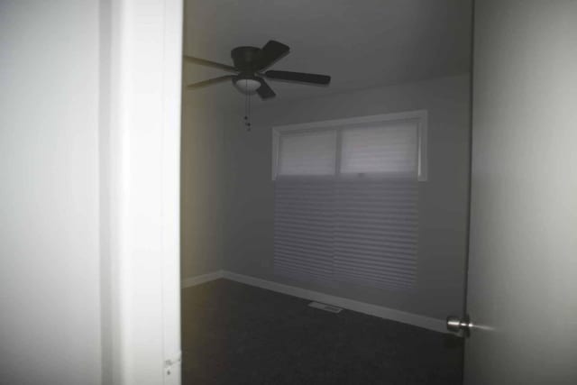 empty room featuring ceiling fan and baseboards