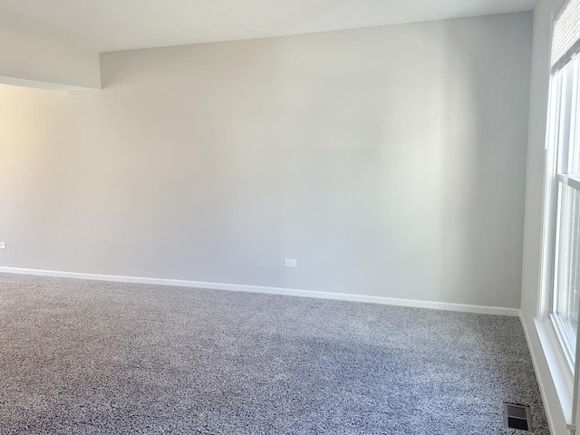 spare room with carpet, visible vents, and baseboards