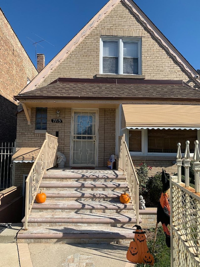 view of front facade featuring a shingled roof and brick siding