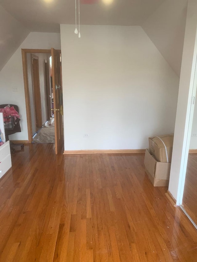 bonus room featuring light wood-type flooring, lofted ceiling, and baseboards