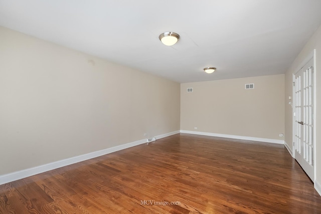 empty room featuring baseboards, visible vents, and wood finished floors