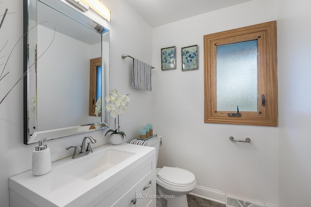 half bathroom featuring visible vents, vanity, toilet, and baseboards