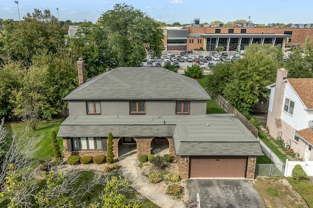 view of front of house with brick siding, a chimney, a gate, fence, and driveway