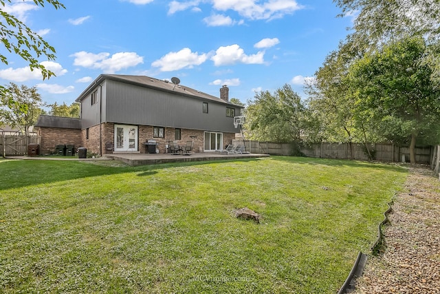 rear view of house with a fenced backyard, a patio, a lawn, and brick siding