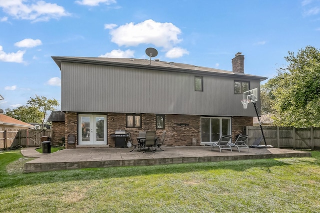 rear view of house with a patio, a fenced backyard, brick siding, french doors, and a lawn