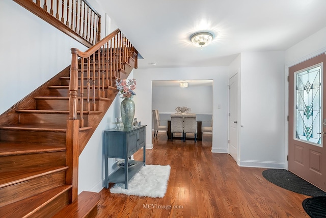 entrance foyer with stairway, wood finished floors, and baseboards