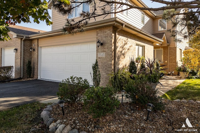 view of home's exterior featuring aphalt driveway, brick siding, and a garage