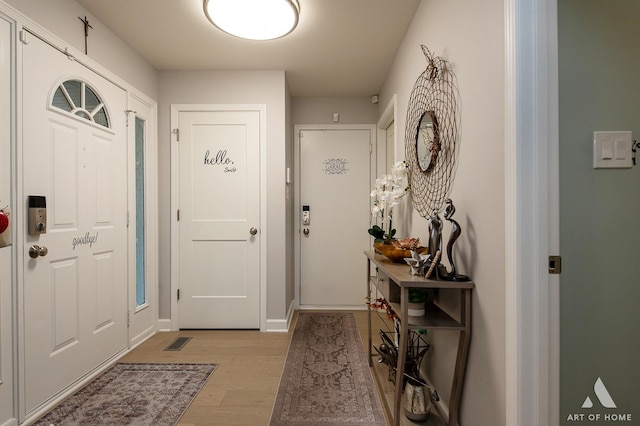 foyer with baseboards and light wood-style floors