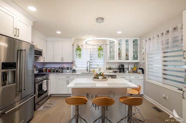 kitchen with visible vents, white cabinets, a breakfast bar area, wood finished floors, and stainless steel appliances