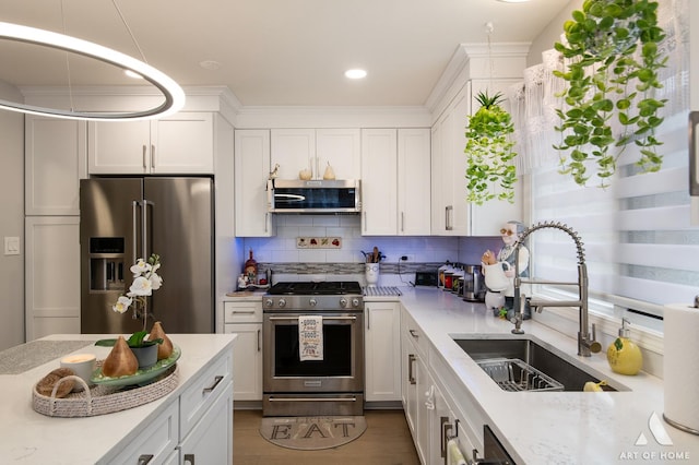 kitchen featuring appliances with stainless steel finishes, white cabinets, a sink, and tasteful backsplash