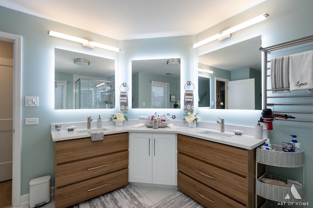 bathroom with double vanity, a shower stall, and a sink