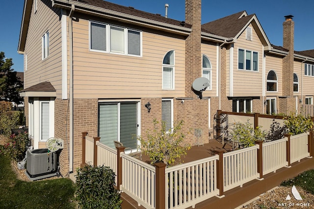 back of property with cooling unit and brick siding