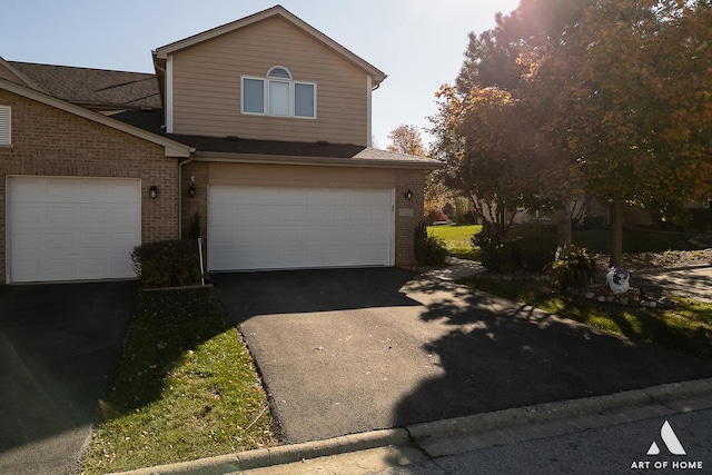 view of front facade with a garage, driveway, and brick siding