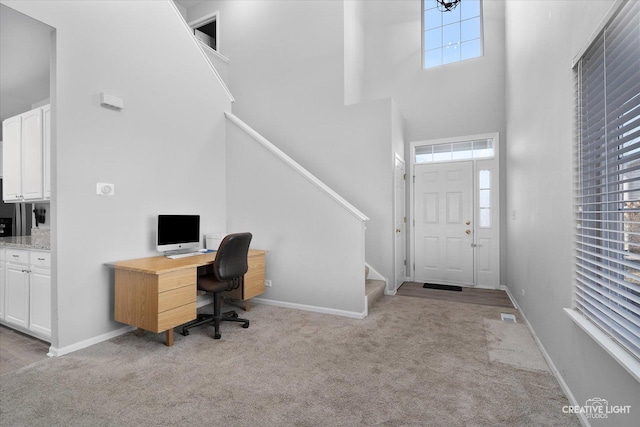 carpeted office with visible vents, baseboards, and a towering ceiling