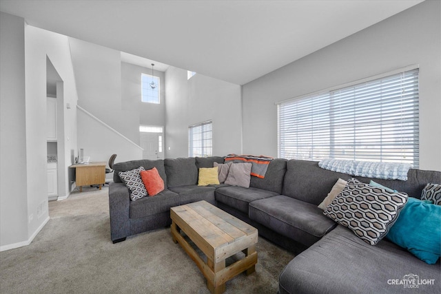 living room featuring light carpet, a high ceiling, and baseboards