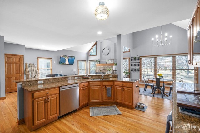 kitchen with brown cabinetry, dishwasher, a notable chandelier, a brick fireplace, and a sink