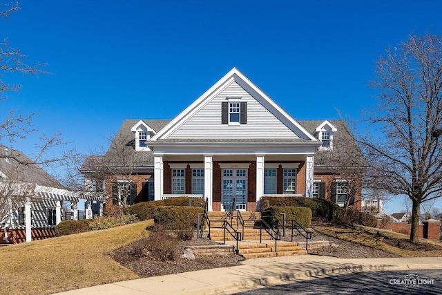 neoclassical / greek revival house with french doors, a porch, brick siding, and a pergola