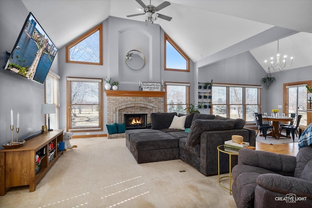 living room with baseboards, carpet flooring, a fireplace, high vaulted ceiling, and ceiling fan with notable chandelier