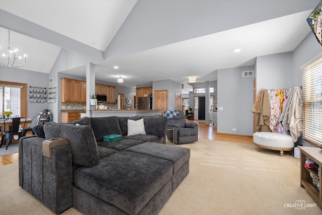 living room with a chandelier, high vaulted ceiling, visible vents, and a wealth of natural light