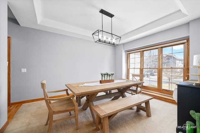 dining area featuring a tray ceiling and baseboards