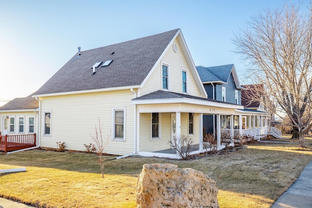 exterior space with covered porch, roof with shingles, and a lawn