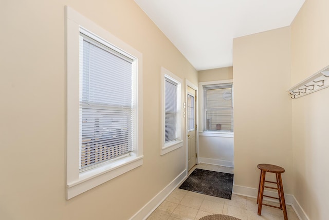 doorway with light tile patterned flooring and baseboards