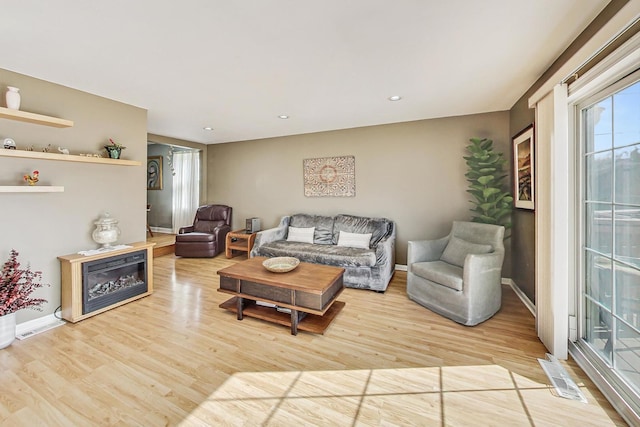 living area with baseboards, visible vents, wood finished floors, and recessed lighting