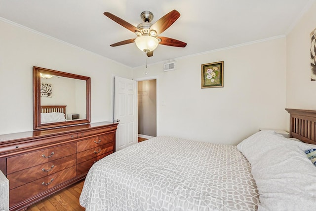 bedroom with ceiling fan, visible vents, crown molding, and wood finished floors