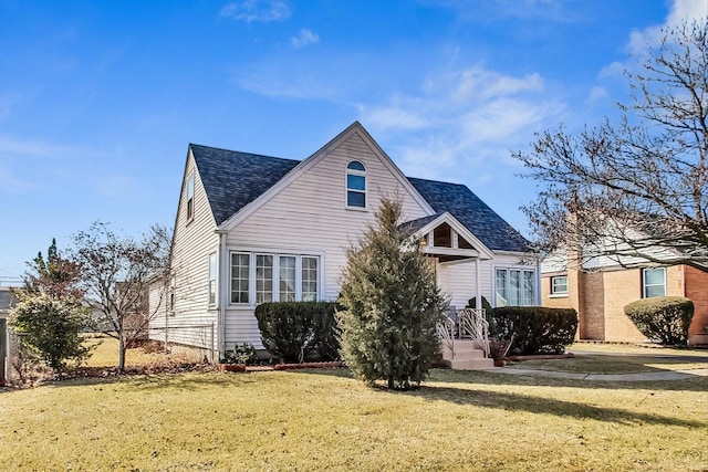 view of front of home with a shingled roof and a front lawn