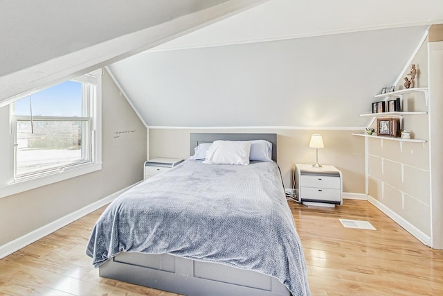 bedroom featuring vaulted ceiling, wood finished floors, visible vents, and baseboards