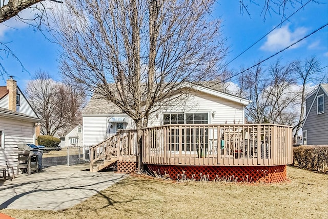 rear view of house featuring fence, a deck, and a lawn